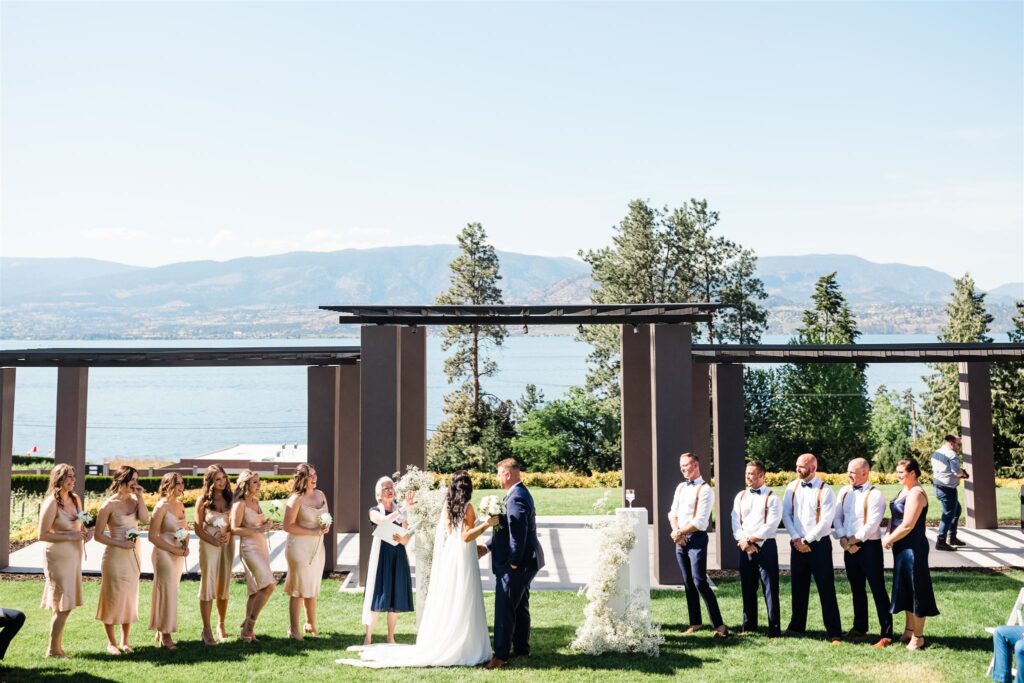 A wedding ceremony at CedarCreek Estate Winery, with a bride, groom and their wedding party.